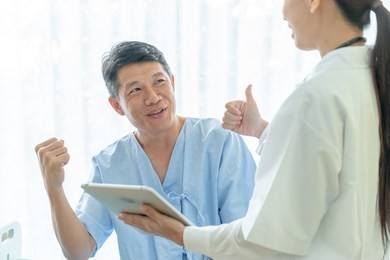 asian senior patient on hospital bed discussing with female doctor - selective focus point