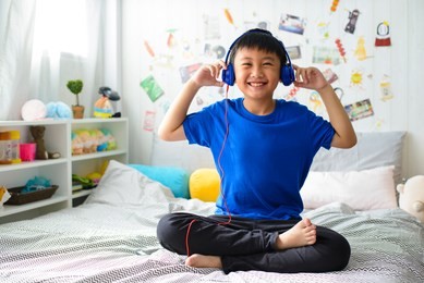 young asian boy is smiling and listening to music