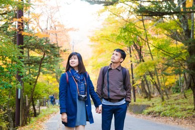 asian couple of love enjoying autumn season colorful tree leaf travel concept