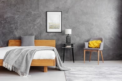 grey blanket and pillow on the wooden bed with white bedding in stylish bedroom interior with concrete wall