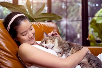 asian woman and tabby cat on sofa