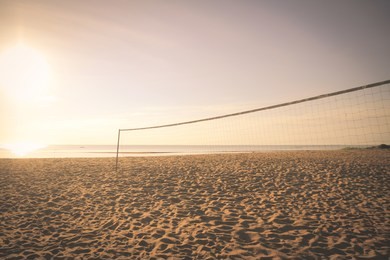 volleyball net on empty beach sand in sunset or sunrise times with vintage filter