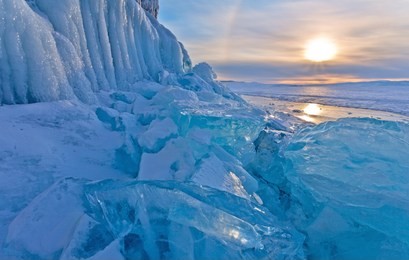 lake baikal is a cold winter afternoon. blue ice hummocks near the icy cliffs of olkhon island at sunset