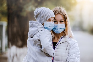 a girl with a child stands on the road in a protective medical mask. dense smog on the streets. epidemic of the flu