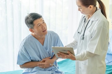 asian senior patient on hospital bed discussing with female doctor - selective focus point