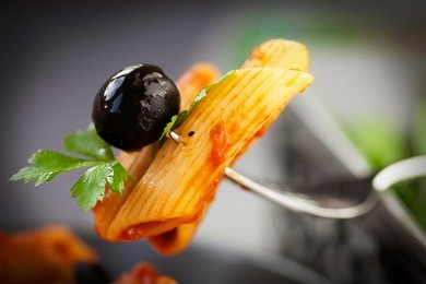italian food. pasta penne with tomato sauce, olives and garnish