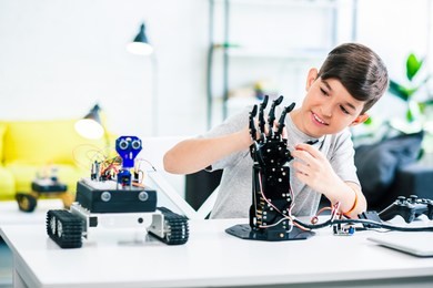 nice optimistic smart boy testing his robotic device while beign involved in engineering classes