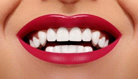 close-up happy female smile with healthy white teeth, bright red gloss lips make-up. cosmetology, dentistry and beauty care. macro of woman's smiling mouth