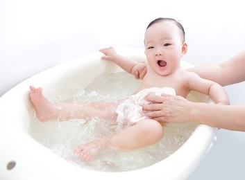 funny face of excite baby girl happy taking a bath by mother at home, asian child