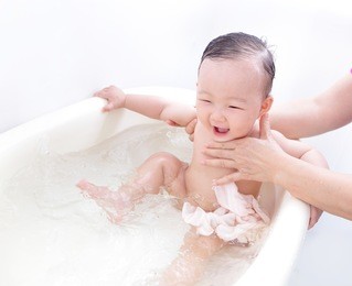 excite baby girl happy taking a bath by mother at home, asian child