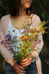 young girl holding a bouquet of wildflowers in hands