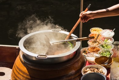 the pot is prepared for cooking. the noodles are in low-light, boiling water with white smoke and steam on black background