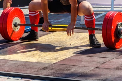 powerlifter preparing for deadlift of barbell during competition of powerlifting