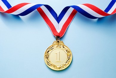 gold medal 1 place with a ribbon on a light blue background, the concept of victory or success