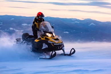 a man is riding snowmobile in mountains. beautiful morning light. blue shadows.