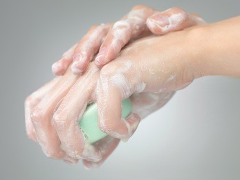 female hands washed with soap o grey gradient background