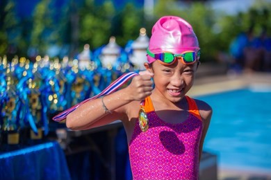 little athlete swimming girl celebrate with golden medal from competition