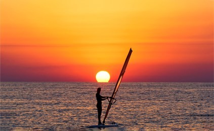 windsurfer sunset silhouette view. sunset windsurfer. windsurfer sunset scene. windsurfer sunset landscape