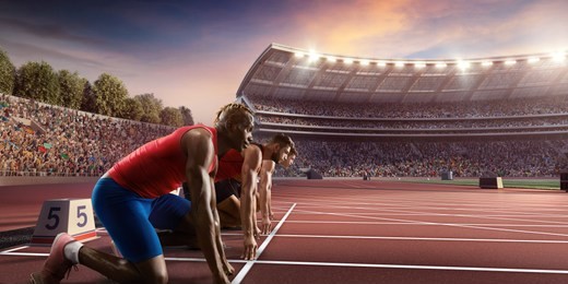 male athletes sprinting. three men in sport clothes on starting line prepares to run at the running track in professional stadium
