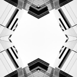 black and white mirror shot of a glass building. the shot was taken whilst looking up at the building. the building is mainly made of glass and black, grey and white lines.