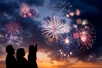 the happy family looks beautiful colorful holiday fireworks in the evening sky with majestic clouds,  long exposure