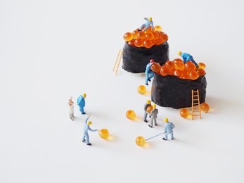 close up miniature people many of worker man making a maki roll over white background,team work concept.