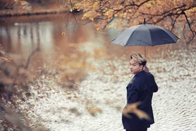 autumn park in rainy weather and a young man with an umbrella
