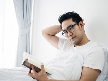 asian man reading a book on bed in weekend, lifestyle concept.