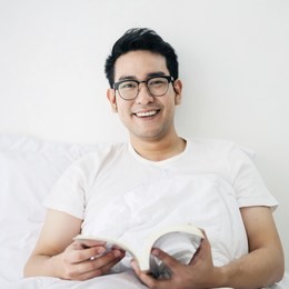 asian man reading a book on bed in weekend, lifestyle concept.