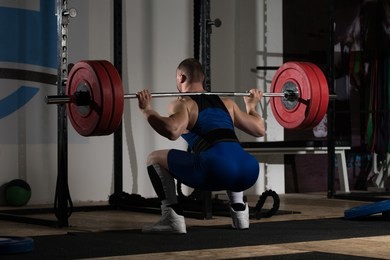powerlifter working out legs with barbell in a gym - squat exercise