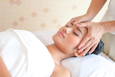 attractive happy relaxing girl at beauty spa treatment. beauty young woman recieving head massage at spa, massager's hands on the woman's head spa concept. young woman with glow, and pefect skin.