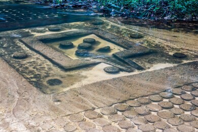 the waterfall flows through the carved statue at kbal spean near siem reap, cambodia