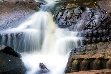 the waterfall flows through the carved statue at kbal spean near siem reap, cambodia