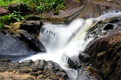 the waterfall flows through the carved statue at kbal spean near siem reap, cambodia