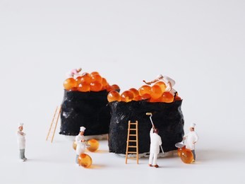 close up miniature people many of worker man making a maki roll over white background,team work concept.
