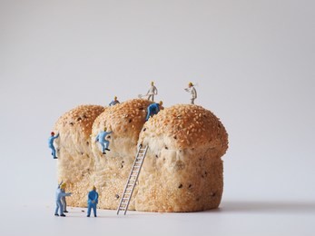 close up miniature people many of worker man working on whole grain bread background,team work concept.