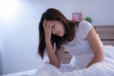 asian woman have a headaches may be migraines in the morning on the bed 