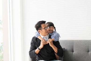 asian father and daughter playing and hug together in livingroom at home.