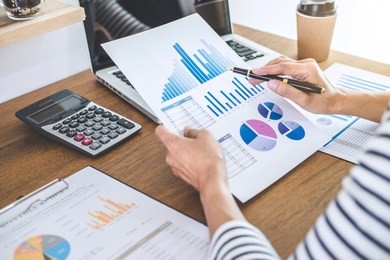 female accountant calculations, audit and analyzing financial graph data with calculator and laptop business, financing, accounting, doing finance, economy, savings banking concept.