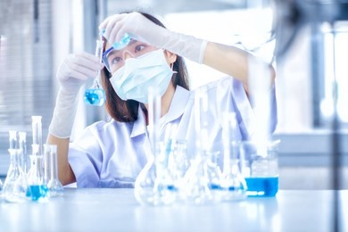 young asian scientist with test tube making research in clinical laboratory.science, chemistry, technology, biology and people concept