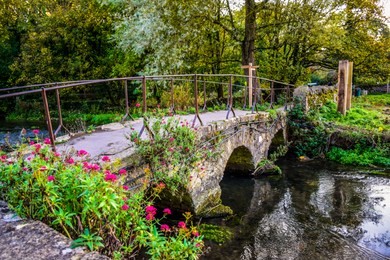 a small vintage stone bridge over river coln that leads to arlington row of bibury village in cotswold district, gloucestershire, england, uk