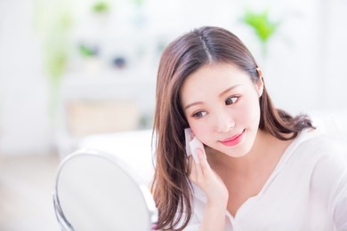 smile woman remove makeup by cleansing cotton and look mirror at home