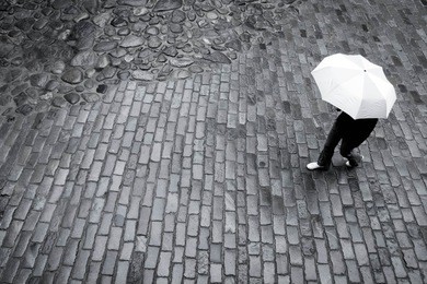woman with umbrella in the rain on paving stone road