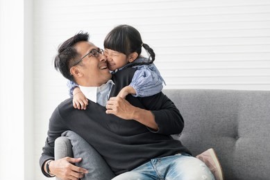 asian father and daughter playing and kiss together in livingroom at home.
