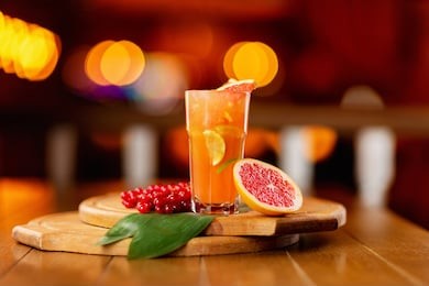 glass of fresh orange juice with lemon, grapefruit and lime on a wooden board at festive blurred background.