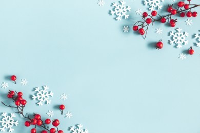christmas or winter composition. frame made of snowflakes and red berries on pastel blue background. christmas, winter, new year concept. flat lay, top view, copy space