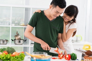 smiling couple spending time together in the kitchen, guy chopping vegetables