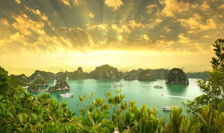beautiful orange sunrise and rock islands in halong bay vietnam. junk boat cruise to ha long bay. exotic scenery. landscape yellow sky. famous landmark of vietnam