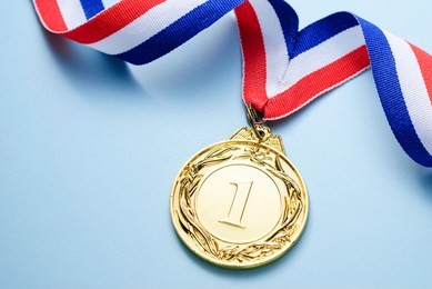 gold medal 1 place with a ribbon on a light blue background, the concept of victory or success
