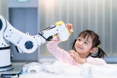 asian little girl touching a robotic machine arm
